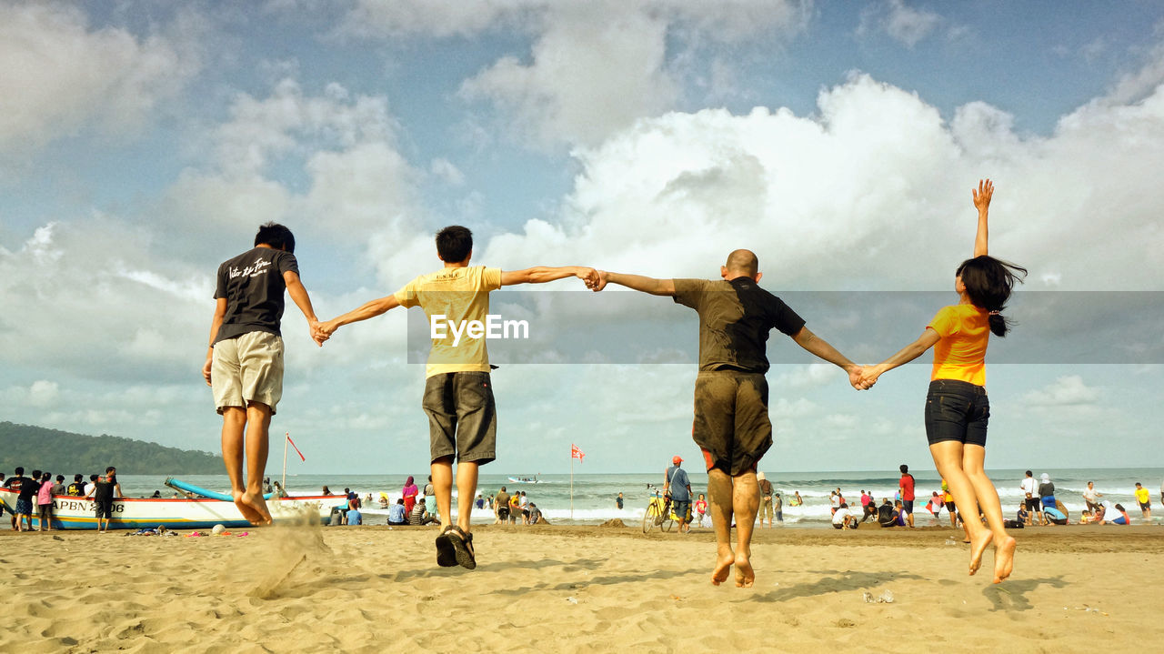 Full length of siblings playing soccer at beach