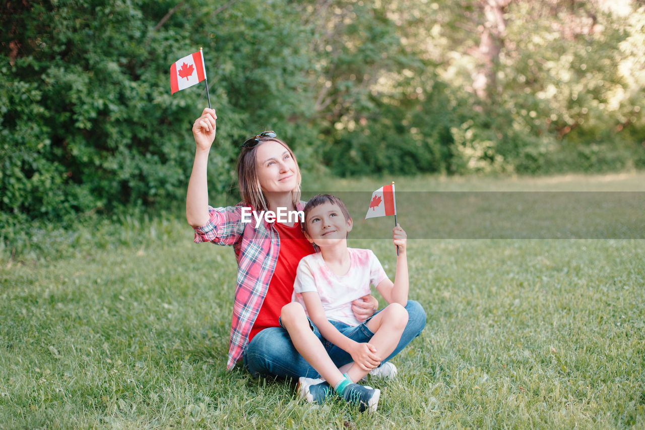 Family mom with son celebrating canada day on 1st of july. mother with child waving canadian flags