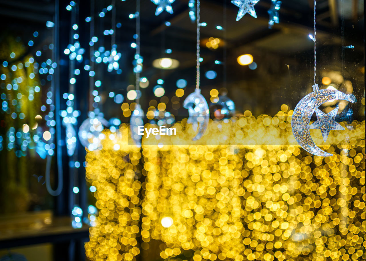 CLOSE-UP OF ILLUMINATED LIGHTING EQUIPMENT HANGING AT NIGHT