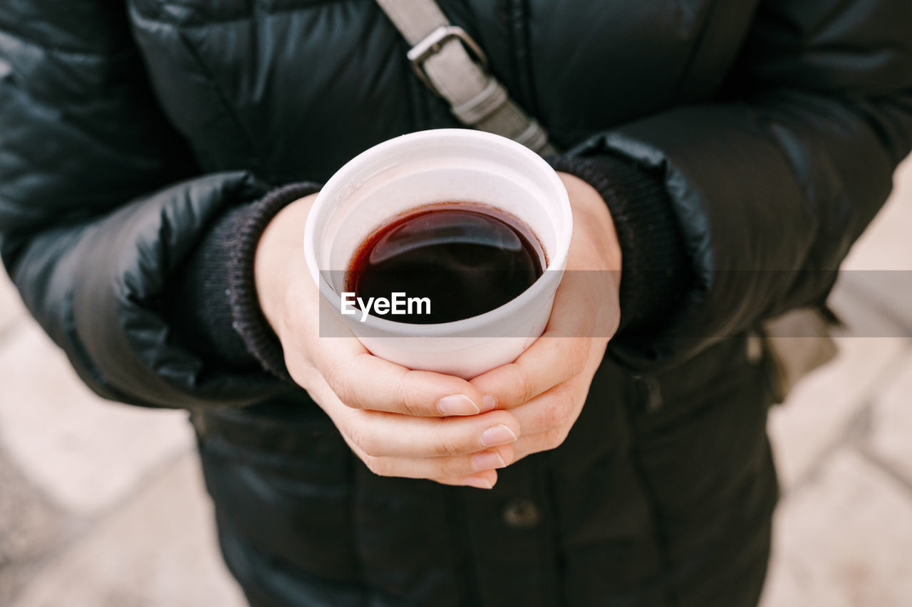 Midsection of man holding coffee cup