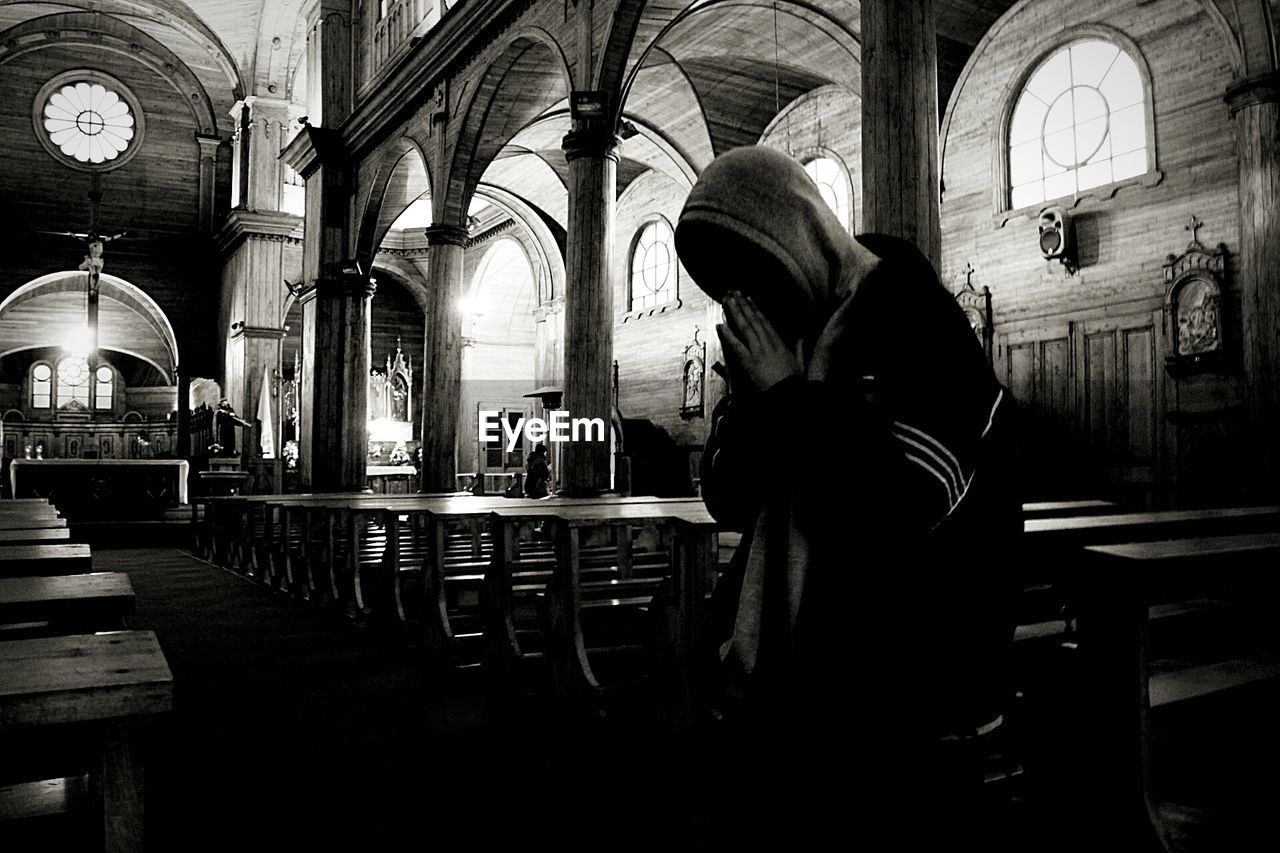 REAR VIEW OF MAN AND WOMAN STANDING IN ILLUMINATED CATHEDRAL