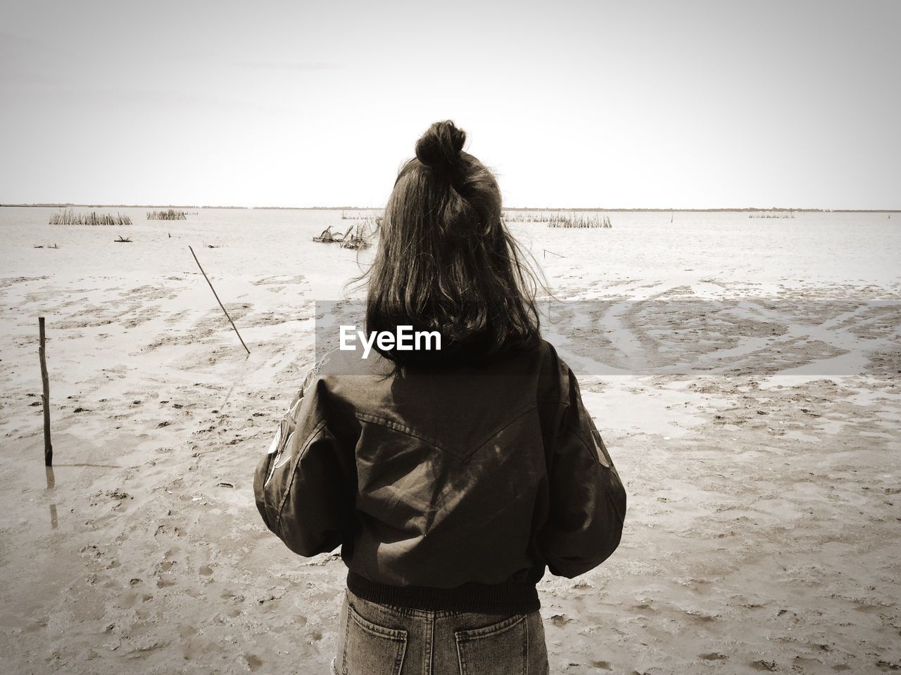 Rear view of woman standing on beach against sky