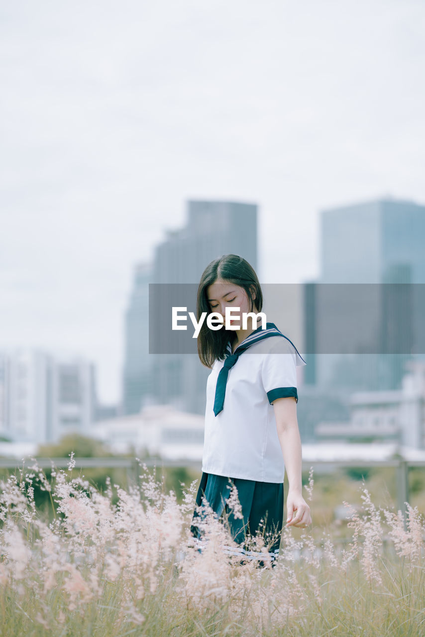 Young woman standing amidst plants on field