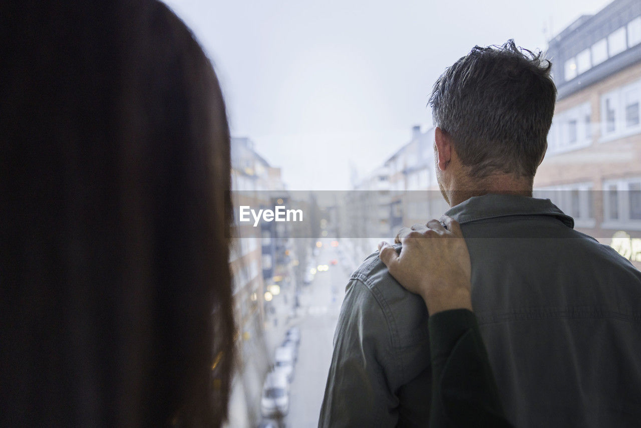 Woman touching man's arm by window