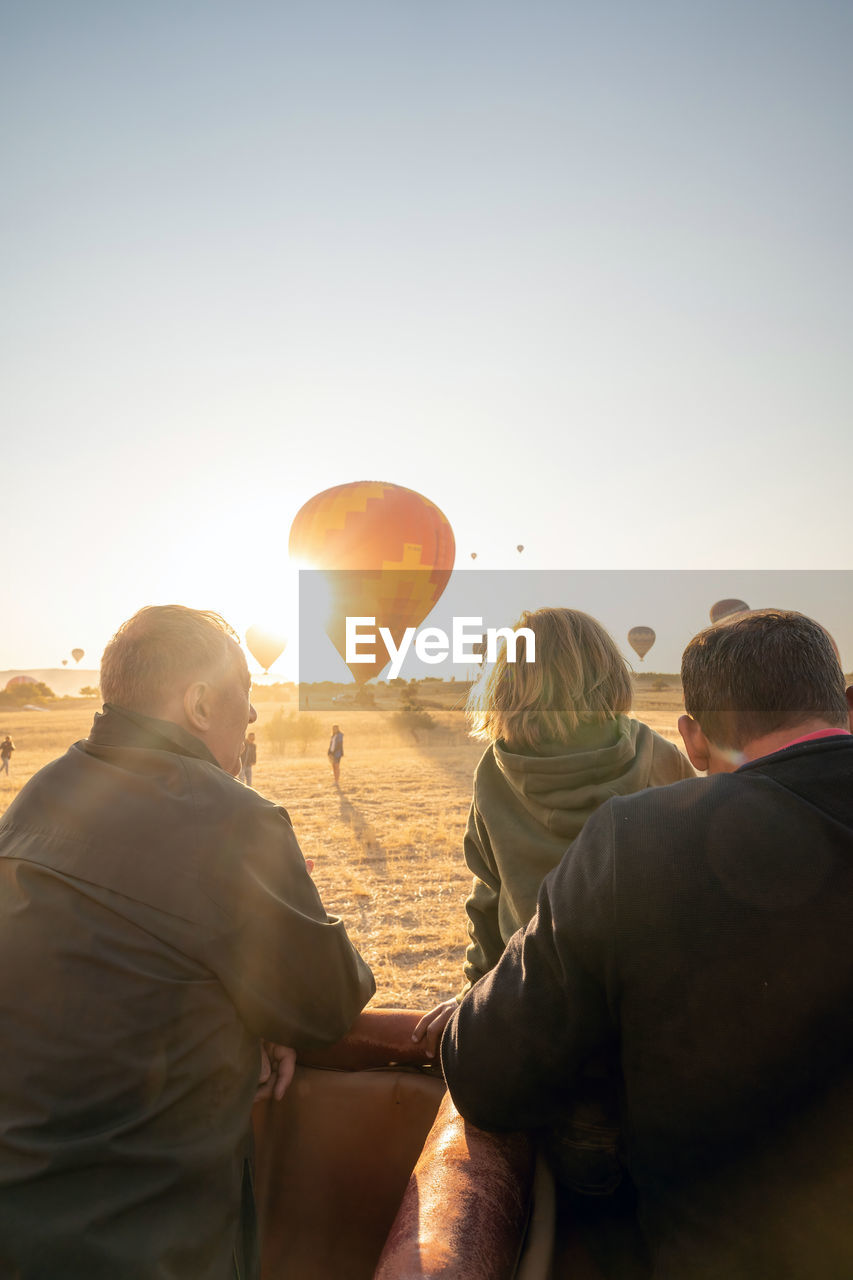 REAR VIEW OF COUPLE AGAINST SKY DURING SUNSET