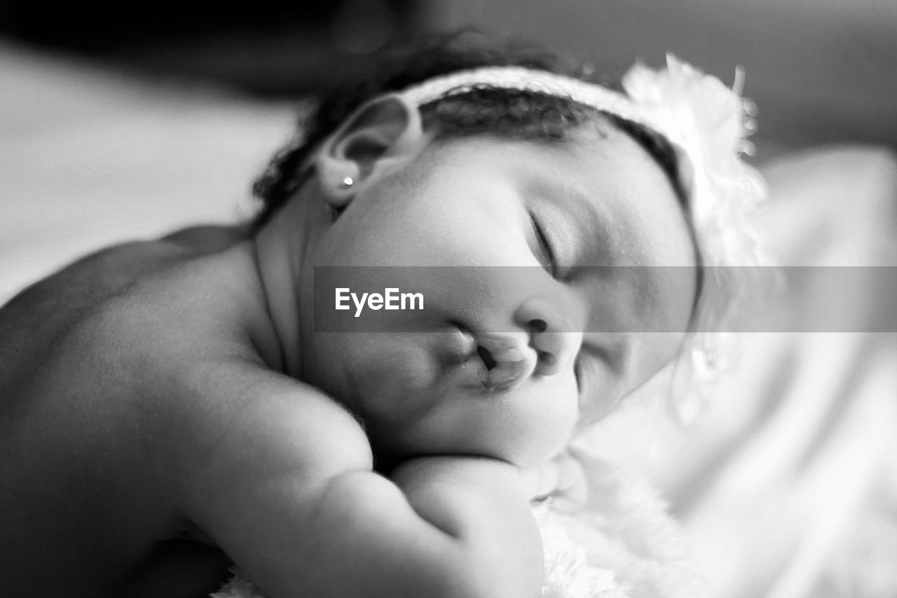 Close-up of cute baby girl sleeping on bed