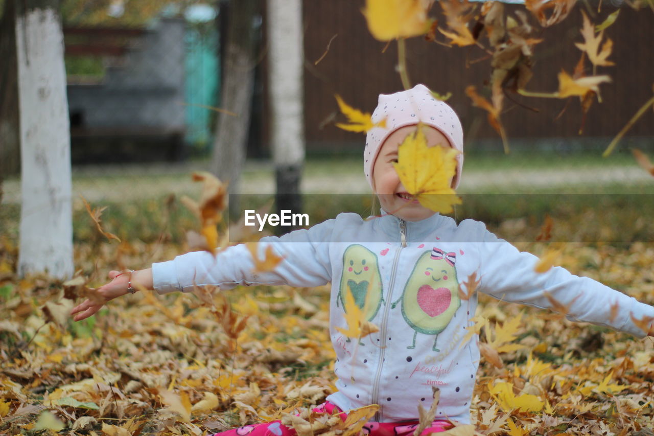 childhood, autumn, child, one person, nature, spring, agriculture, leaf, cute, yellow, innocence, plant part, plant, clothing, flower, land, front view, toddler, baby, fun, day, outdoors, field, female, scarecrow, women, tree, lifestyles, leisure activity, focus on foreground, hat, smiling, full length, casual clothing, happiness, arm, limb, celebration, emotion, costume