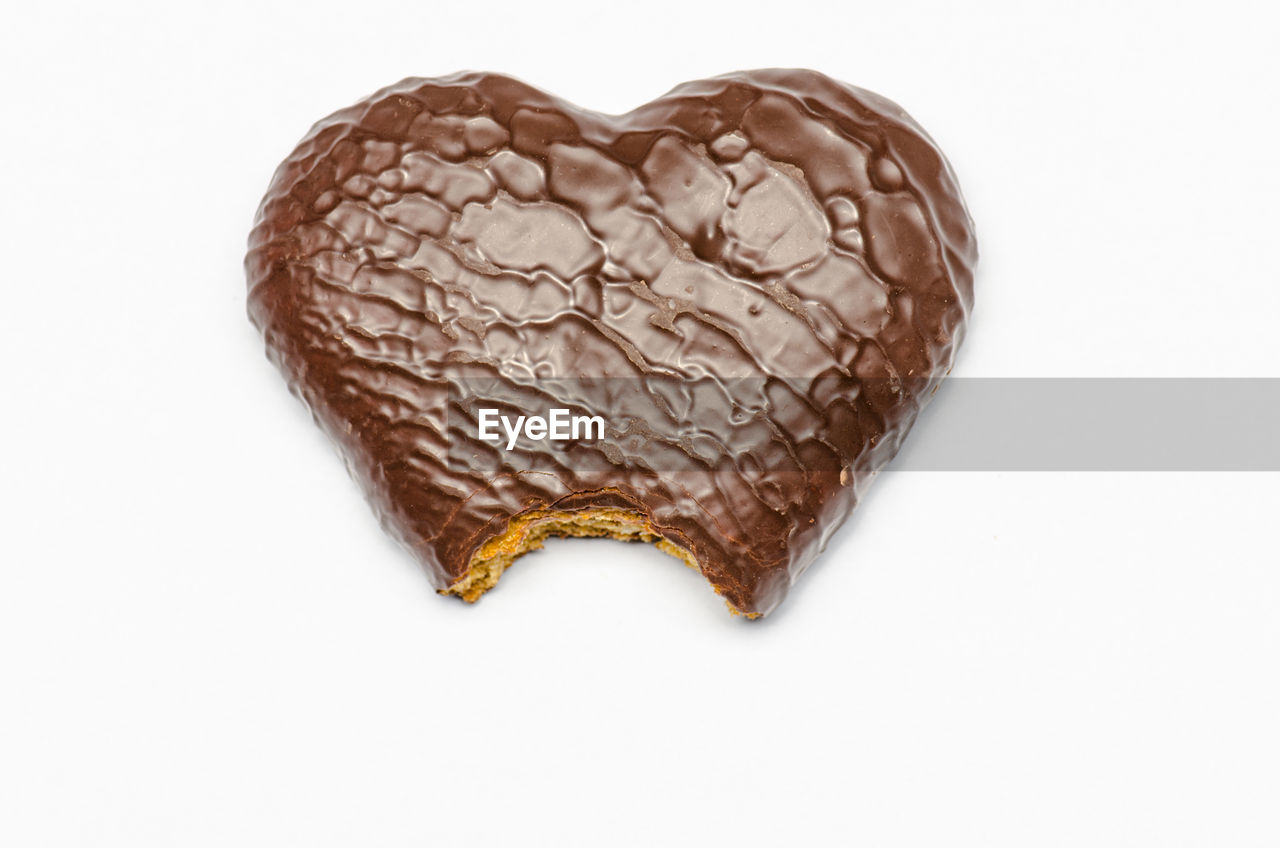 Close-up of heart shape dessert over white background