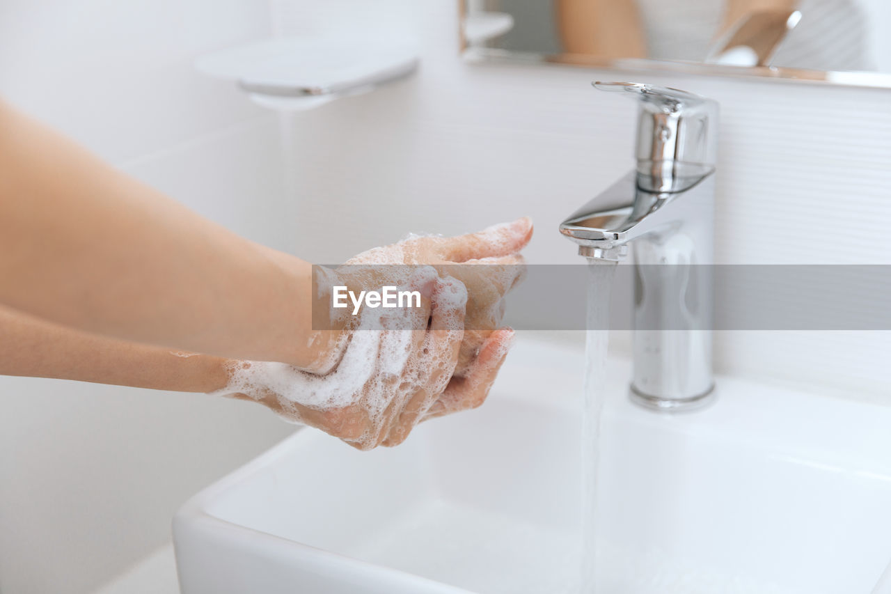 Cropped hand washing hands in sink