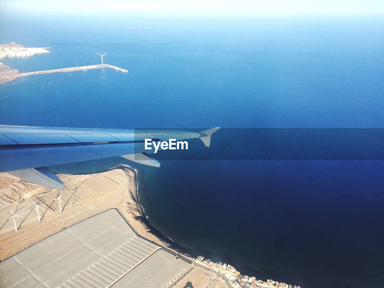 Cropped image of airplane flying above sea and landscape