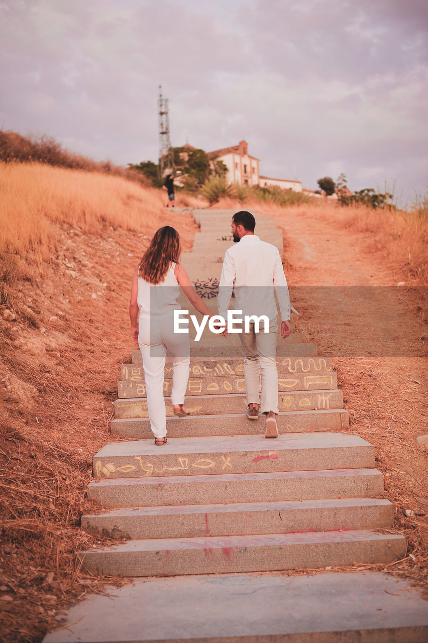 Rear view full length of young couple moving up on steps