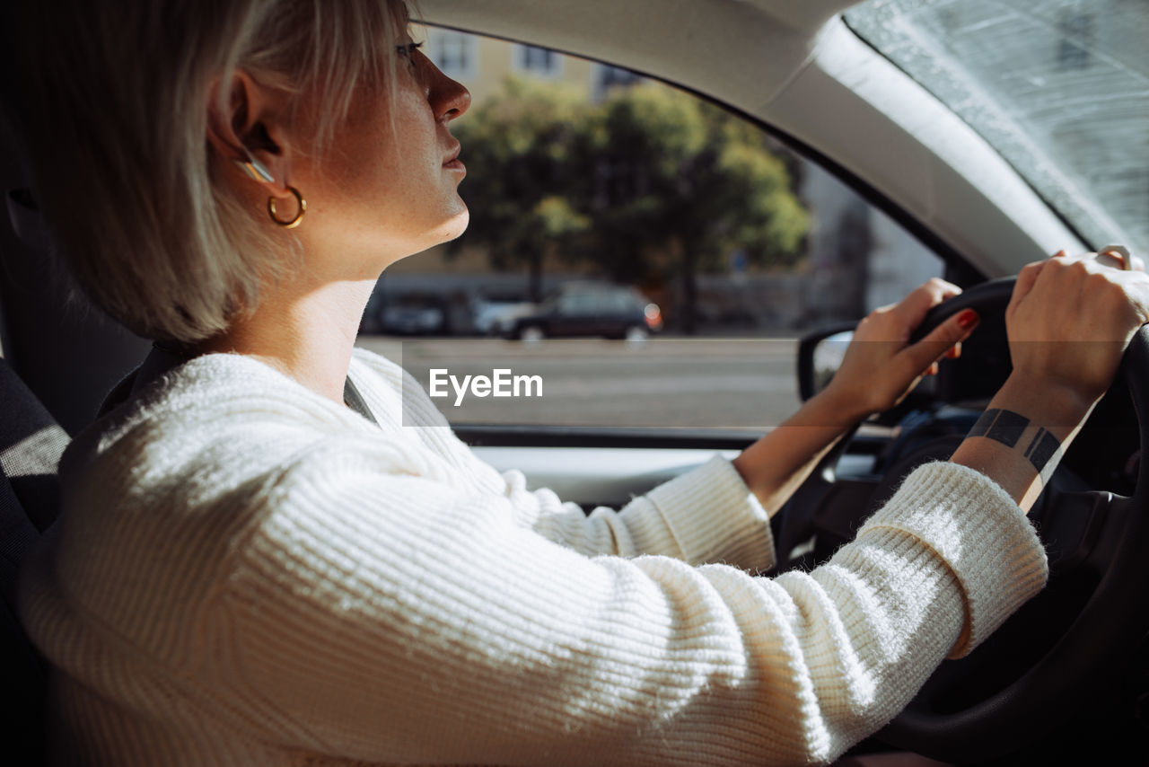 Inside view of a blond caucasian woman driving a car