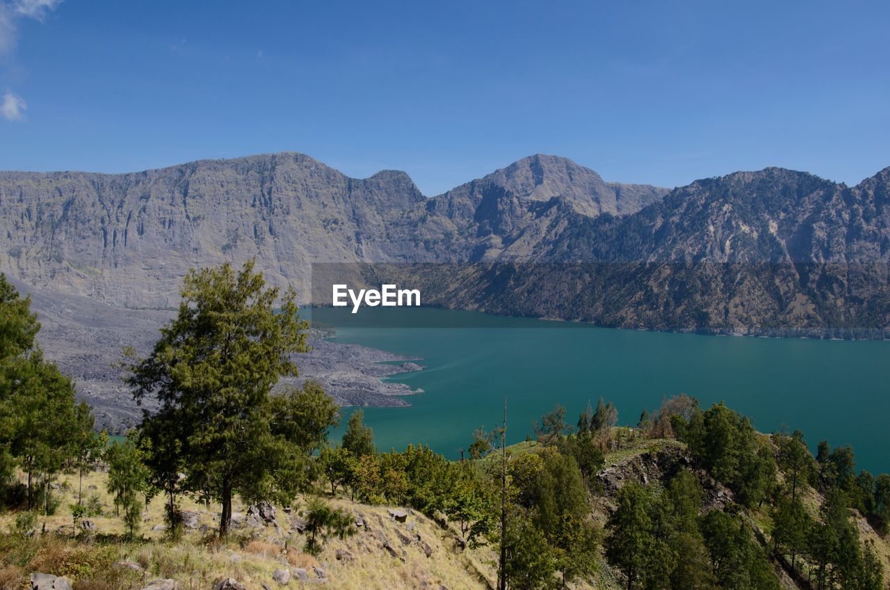 Scenic view of lake and mountains against blue sky