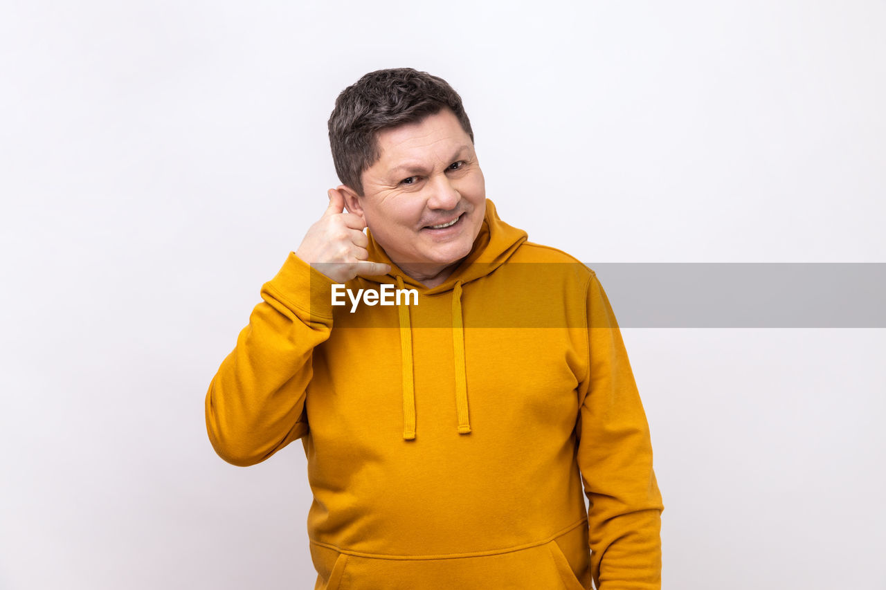 one person, yellow, studio shot, adult, sleeve, clothing, smiling, portrait, emotion, happiness, men, indoors, waist up, outerwear, copy space, white background, hood, person, casual clothing, lifestyles, front view, cheerful, positive emotion, standing, looking, young adult