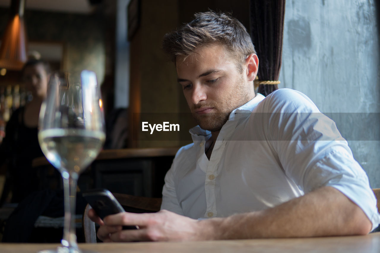 PORTRAIT OF A YOUNG MAN SITTING AT RESTAURANT