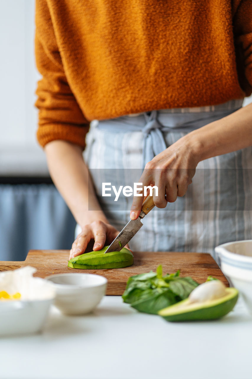 Woman cutting avocado on cutting board