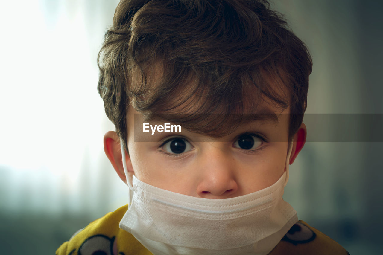Close-up portrait of cute boy wearing mask at home