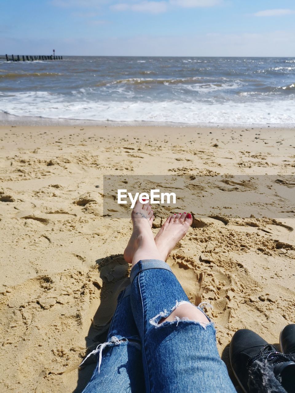 LOW SECTION OF WOMAN LYING ON BEACH