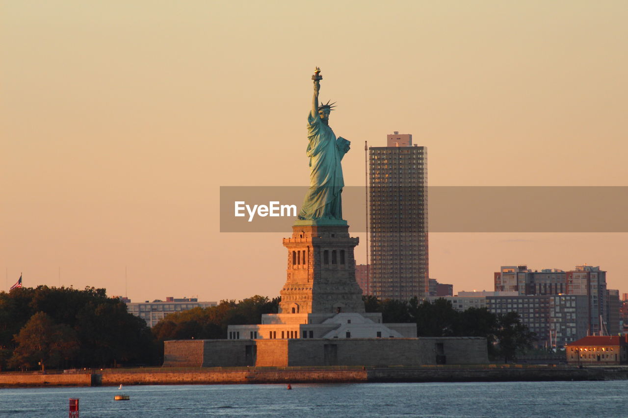 Statue in city against clear sky