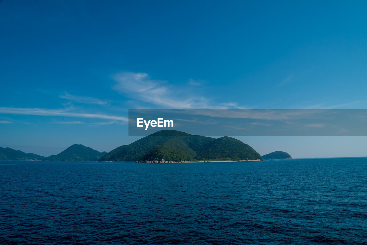 SCENIC VIEW OF SEA AND MOUNTAINS AGAINST BLUE SKY