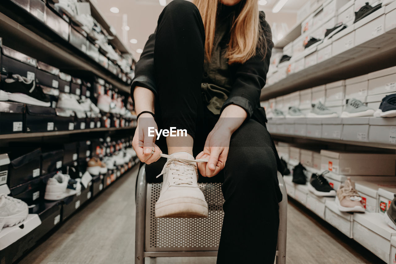 Midsection of woman tying shoelace in store