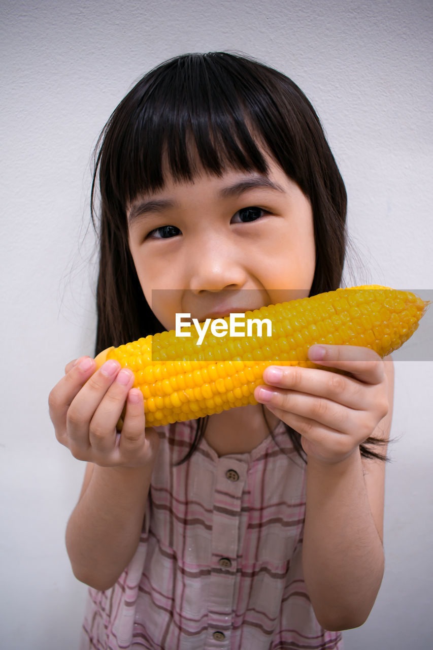 Close-up portrait of smiling girl eating corn