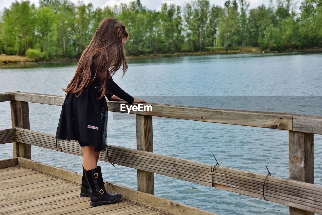 Side view of woman standing on pier over lake