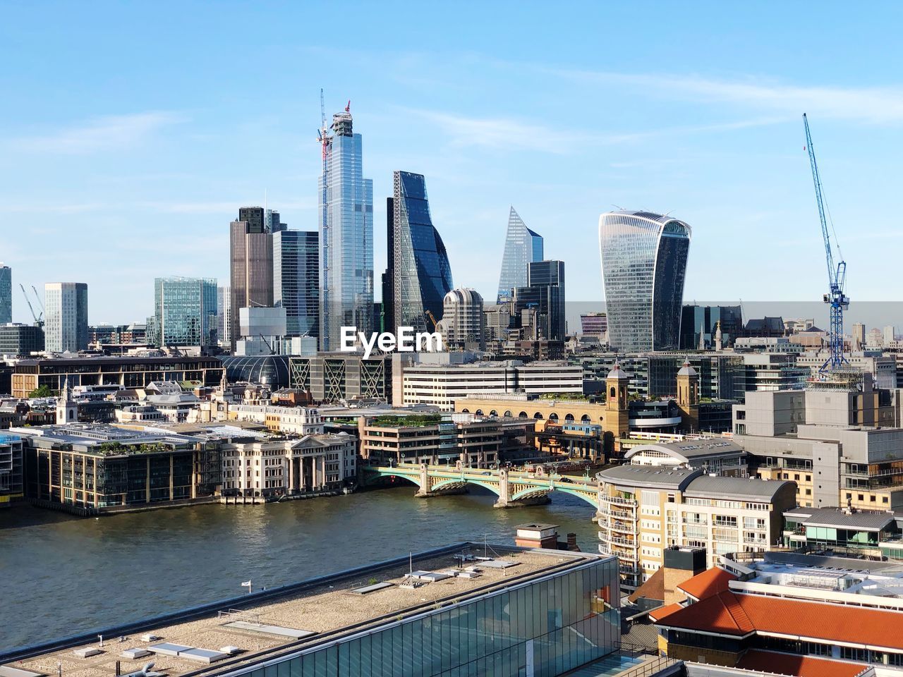 Modern buildings by river against sky in city