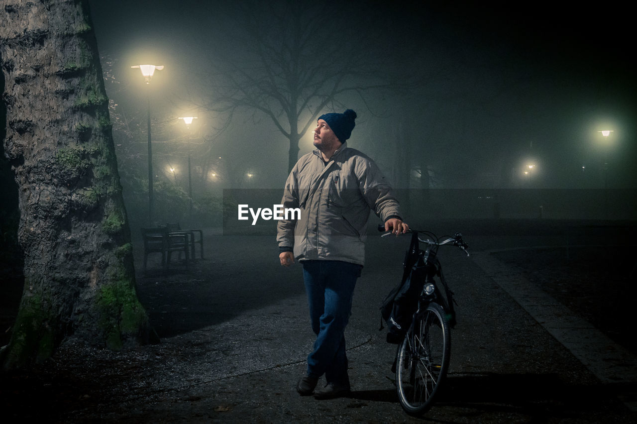 Man standing with bicycle at night