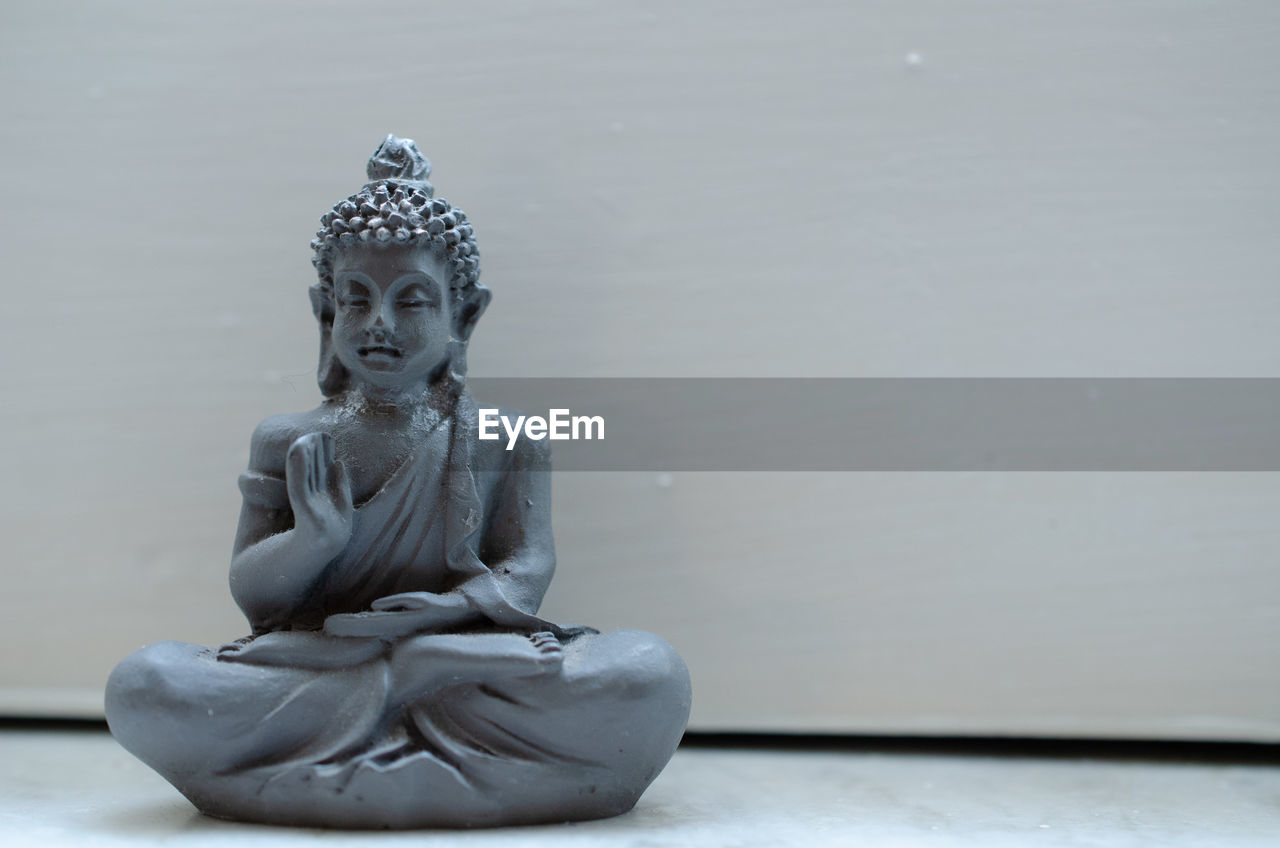 CLOSE-UP OF BUDDHA STATUE AGAINST WALL