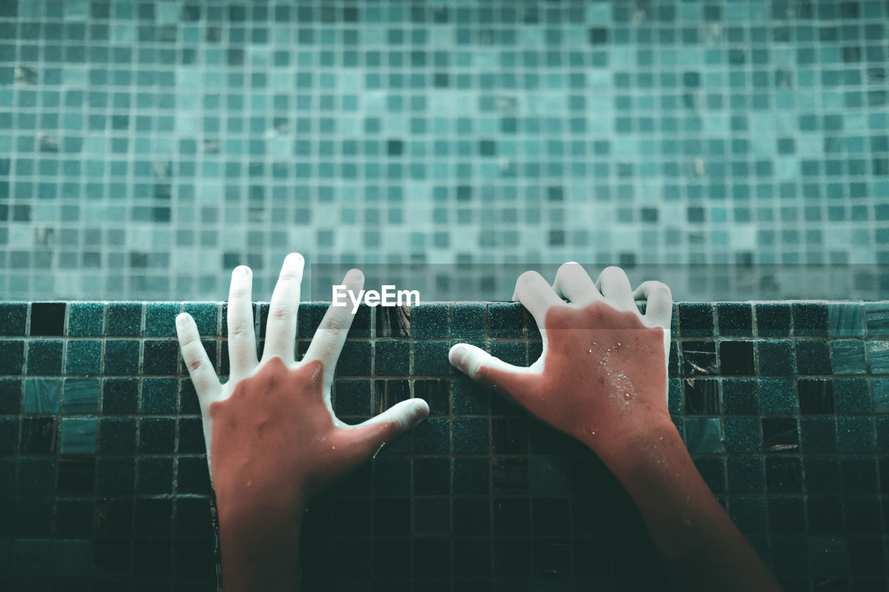 Directly above shot of hands in illuminated swimming pool