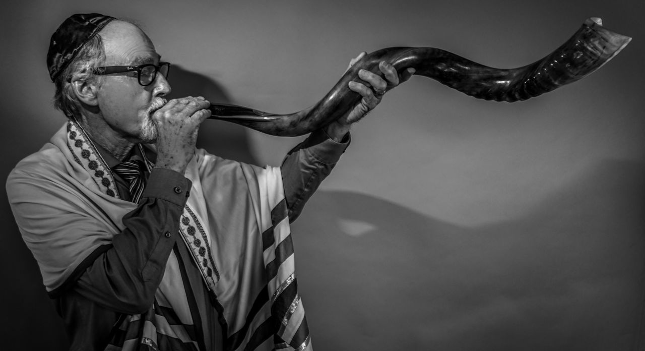 Man playing shofar against wall