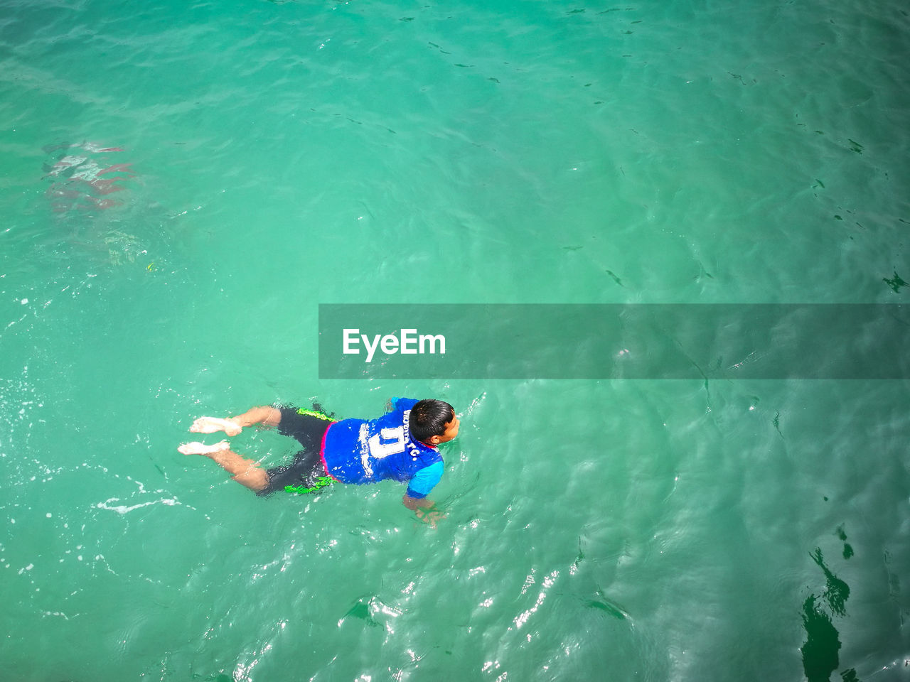 HIGH ANGLE VIEW OF MAN SWIMMING IN WATER