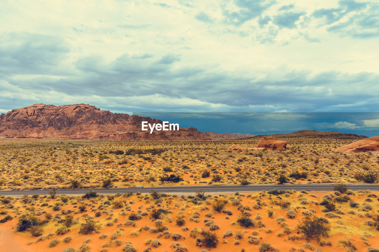 SCENIC VIEW OF ARID LANDSCAPE AND MOUNTAINS AGAINST SKY