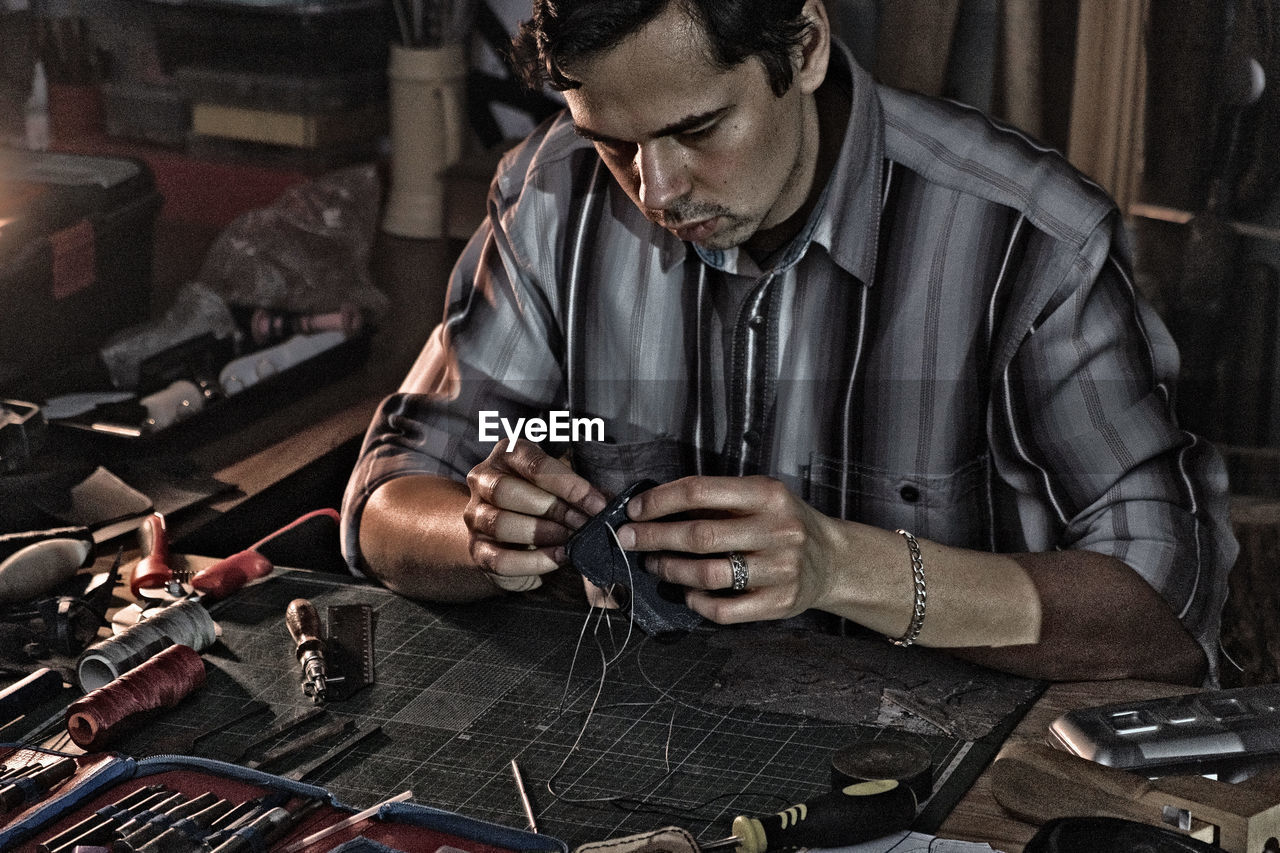 Man working with leather at table in workshop