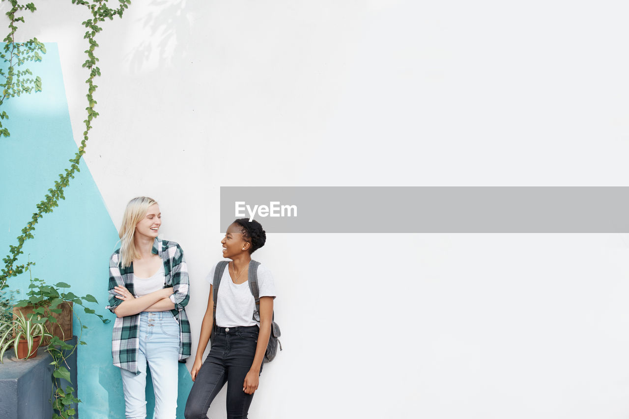 Smiling female friends against wall