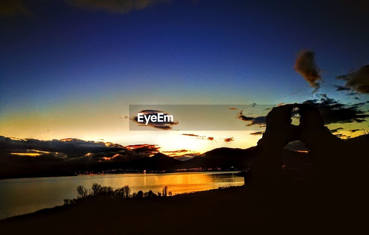 SCENIC VIEW OF LAKE AGAINST SKY AT SUNSET