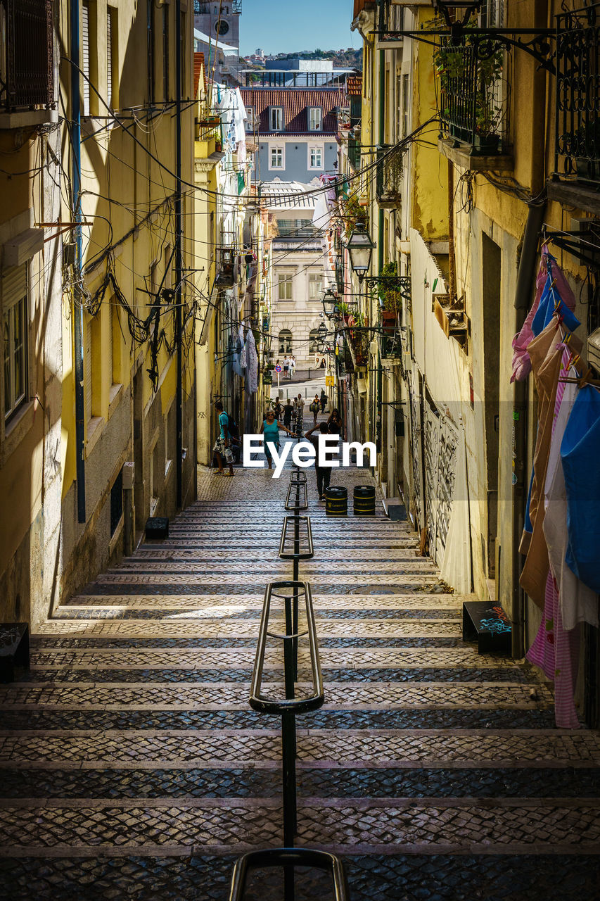 People walking on steps amidst buildings in city