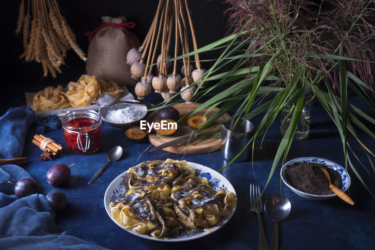 Sweet pasta dessert, noodles with poppy seeds, plum compote, close-up of the food on table.