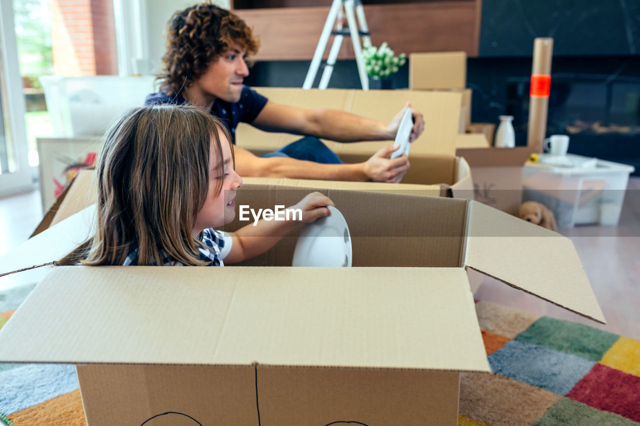 Father and son with plates sitting in cardboard boxes at home