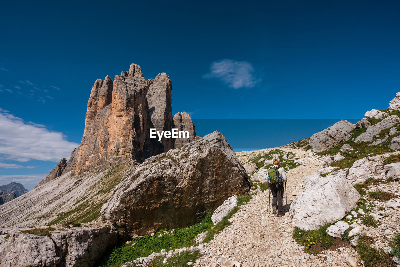 Rear view of woman walking on rock against sky