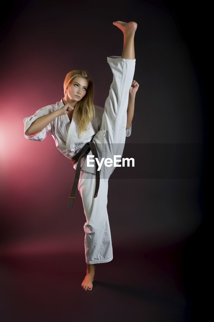 Full length of flexible woman practicing karate