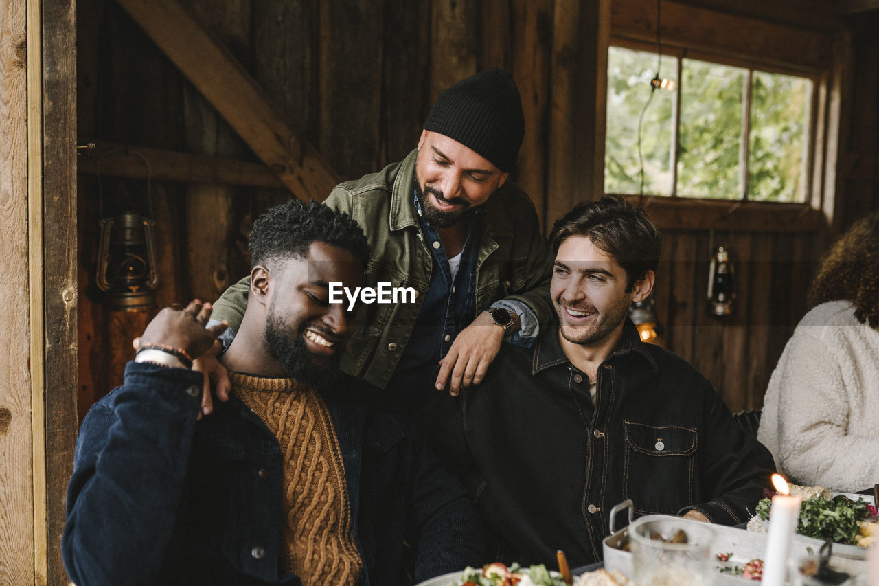 Smiling man talking to male friends at dinner party