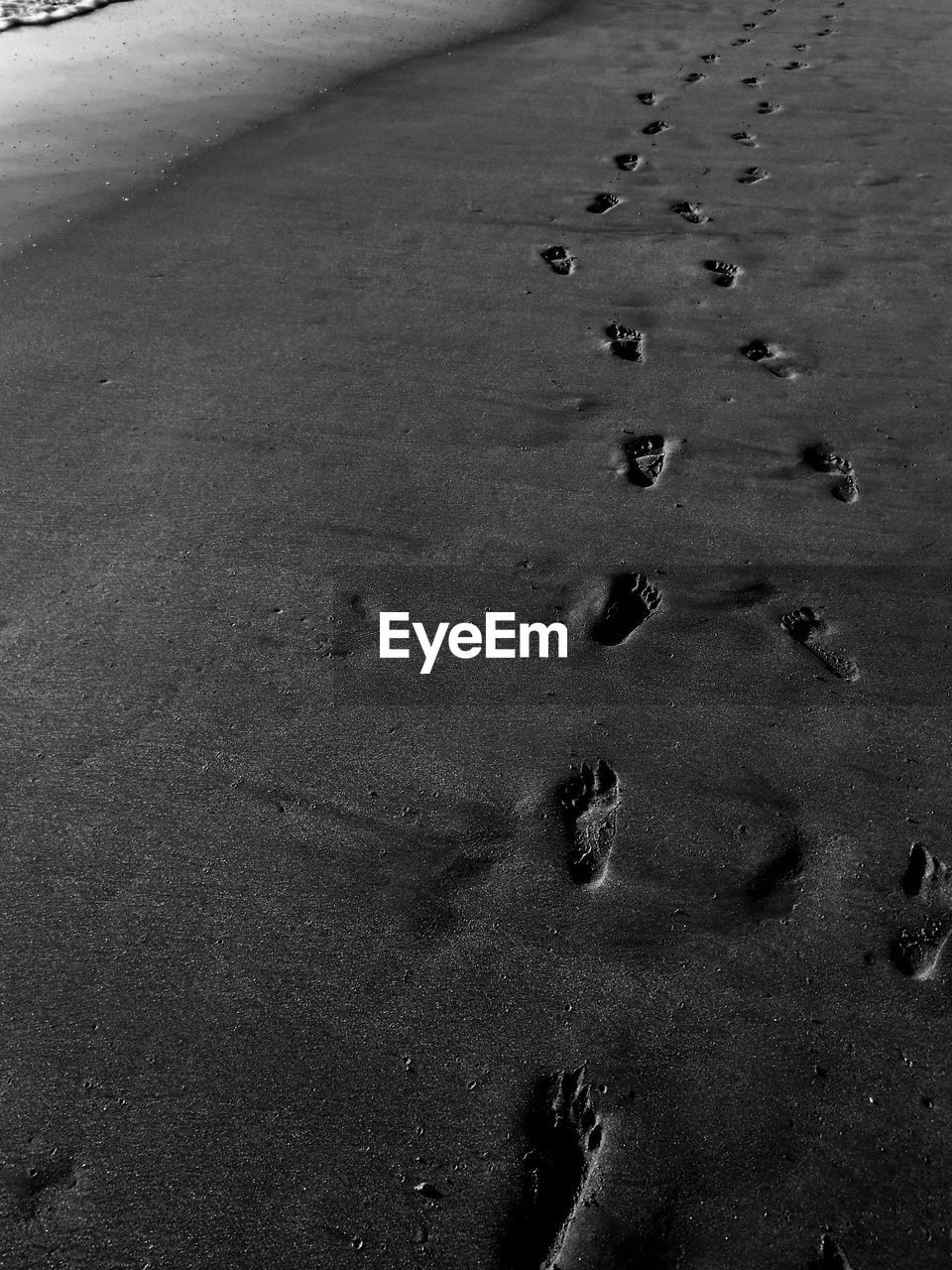 High angle view of footprints on wet sand