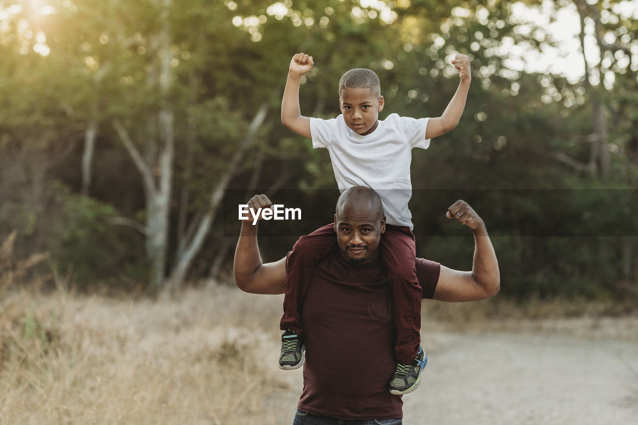 Close up portrait of school-aged son sitting on father's shoulders