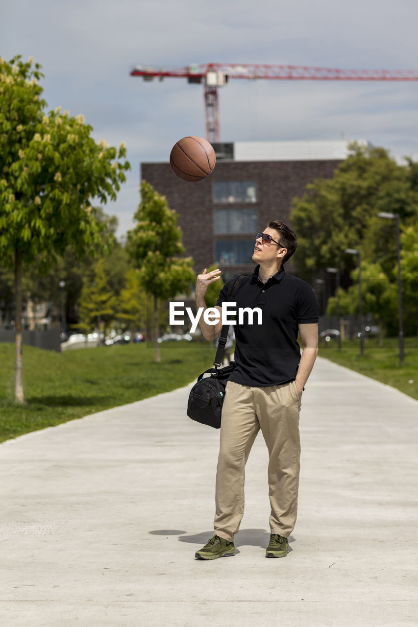 Close-up of mature man throwing basketball while standing outdoors