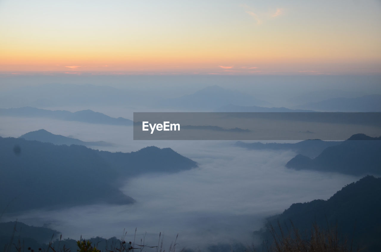 Scenic view of clouds and mountains against sky during sunset