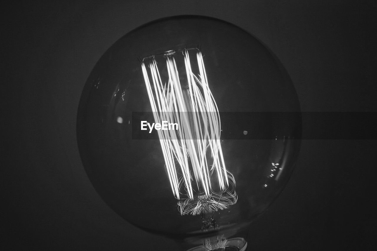 Close-up of illuminated light bulb against black background