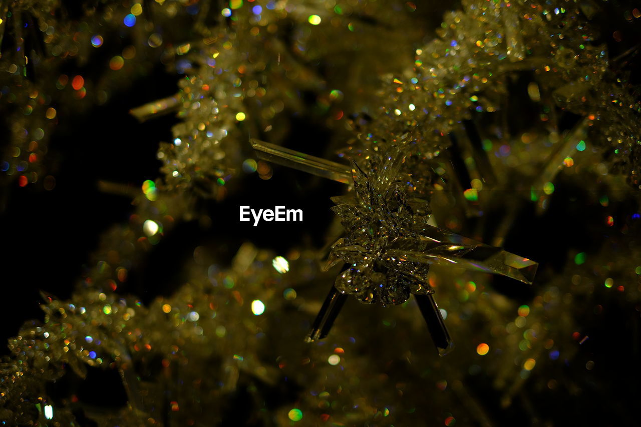 CLOSE-UP OF ILLUMINATED CHRISTMAS TREE AGAINST BLURRED LIGHTS