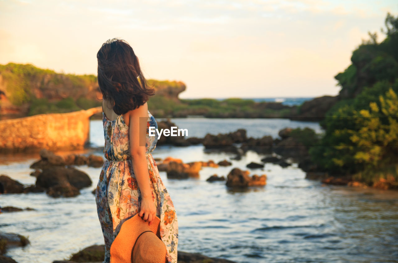 Rear view of woman standing by river